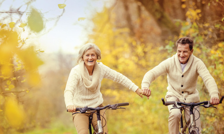Senior couple holding hand while biking in the fall
