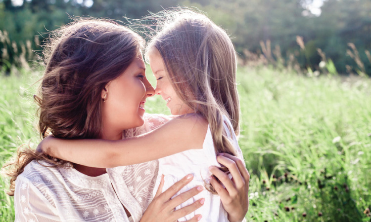 Mother and daughter happy in a field in summer