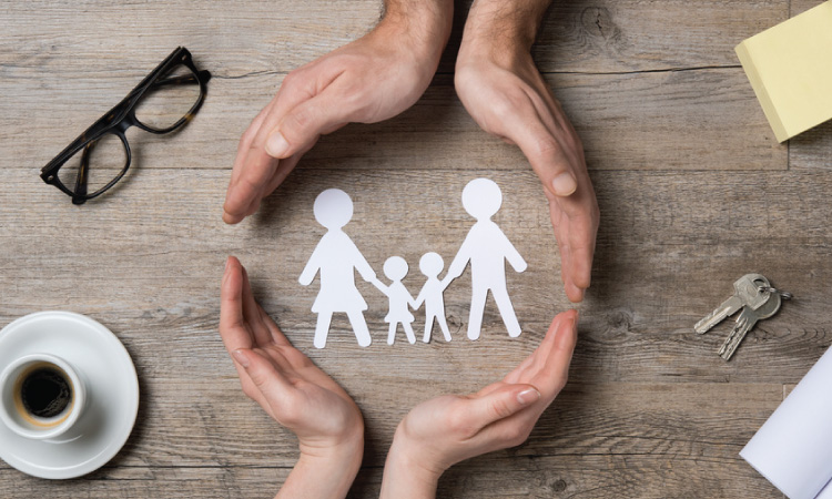 coulple hands on table surrounding paper silhouettes of family.