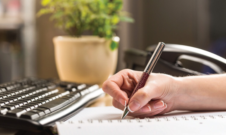 A person's hand writing in a notebook